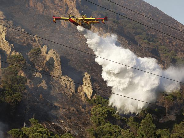 Ein Löschflugzeug wirft Wasser über einem Waldbrand auf einem Berg in Altofonte in der Nähe von Palermo.