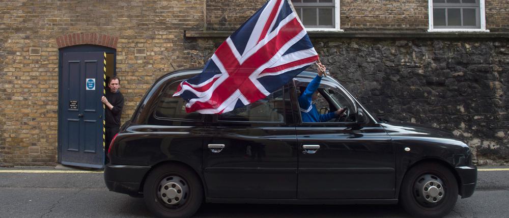 Ein Taxifahrer hält eine britische Flagge aus dem Fenster.