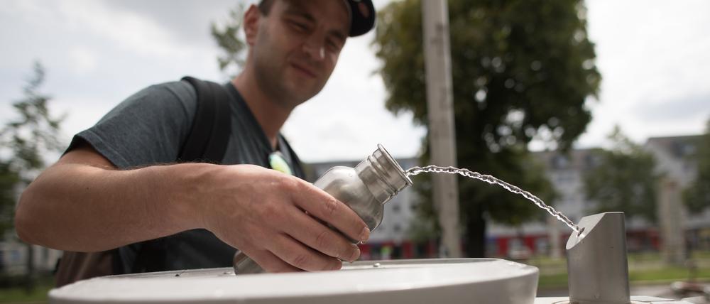 Ein Passant füllt seine Tinkflasche an einem Brunnen der Berliner Wasserbetriebe.