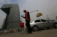 Ein chinesischer Bauarbeiter geht an einem der markantesten Bauwerken in Peking vorbei, dem Gebäude des chinesischen Staatsfernsehens CCTV. Foto: dpa
