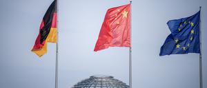 Die Flaggen Deutschlands, Chinas und der EU in Berlin, im Hintergrund die Kuppel des Reichstagsgebäudes. Chinesische Investoren schränken nach einer Studie der Unternehmensberatung EY ihre Firmenkäufe in Europa immer weiter ein. 