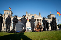 Eine Teilnehmerin wird von Polizeibeamten mit Mund-Nasen-Schutz vor dem Reichstagsgebäude am Rande einer Demonstration gegen eine Impfpflicht und gegen die freiheitseinschränkenden Maßnahmen der Bundesregierung im Rahmen der Ausbreitung des Coronavirus abgeführt. Foto: Kay Nietfeld/dpa