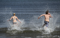 Junge Leute rennen bei frühlingshaftem Wetter am 1. Mai in die Ostsee in Ahlbeck, Mecklenburg-Vorpommern. Foto: dpa/Stefan Sauer
