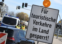 Polizeibeamte kontrollieren hinter einem Schild mit der Aufschrift "Für touristische Verkehre im Land gesperrt!" die Zufahrt zur Insel Usedom. Foto: dpa