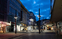 Ein Mann geht in der sogenannten blauen Stunde in Witten an den Geschäften in der ansonsten leeren Fußgängerzone vorbei. Foto: Jonas Güttler/dpa