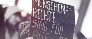 Eine Frau hält am 15.10.2015 in der Innenstadt in Hamburg während einer Demonstration gegen die Verschärfung des Asylrechts ein Schild mit der Aufschrift „Menschenrechte sind für alle da“. Zuvor hatte der Bundestag ein Paket mit umstrittenen Änderungen im Asylrecht beschlossen.