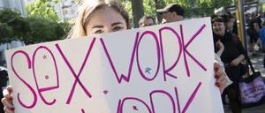 Eine Teilnehmerin an der Demonstration von Sexarbeiterinnen gegen das Prostituiertenschutzgesetz am Internationalen Hurentag hält ein Plakat, darauf steht „sex work is work“.
