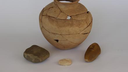 Der Krug aus der jordanischen Wüste enthielt ein Bruchstück eines Mahlsteins („Läufer“, links) eine Muschelschale aus dem Euphrat (Mitte) und einen bearbeiteten Kieselstein (rechts). 
