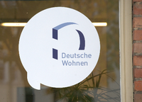 Logo der umstrittenen Immobiliengesellschaft "Deutsche Wohnen" auf einer Fensterscheibe. Foto: Paul Zinken/dpa