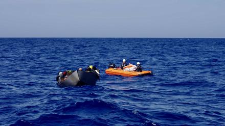 Ein Rettungsboot des Motorsegelschiffs „Nadir“ begleitet ein überfülltes Stahlboot im Mittelmeer.