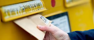 Ein Briefumschlag wird in einen Briefkasten geworfen. 