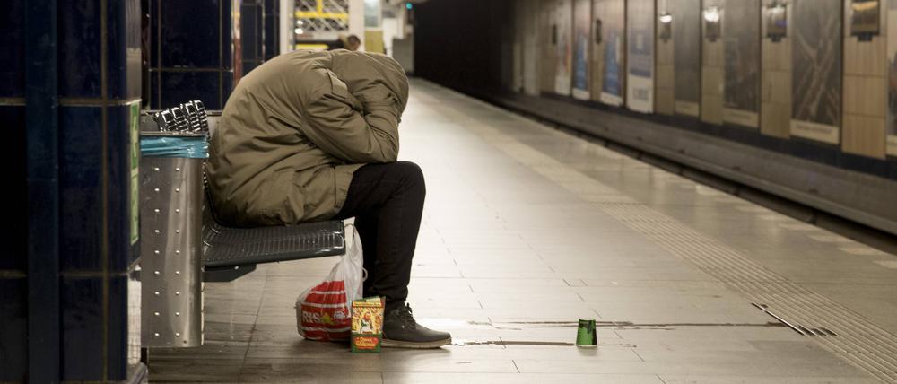 Ein Obdachloser sitzt auf einer Bank in einem U-Bahnhof in Neukölln.