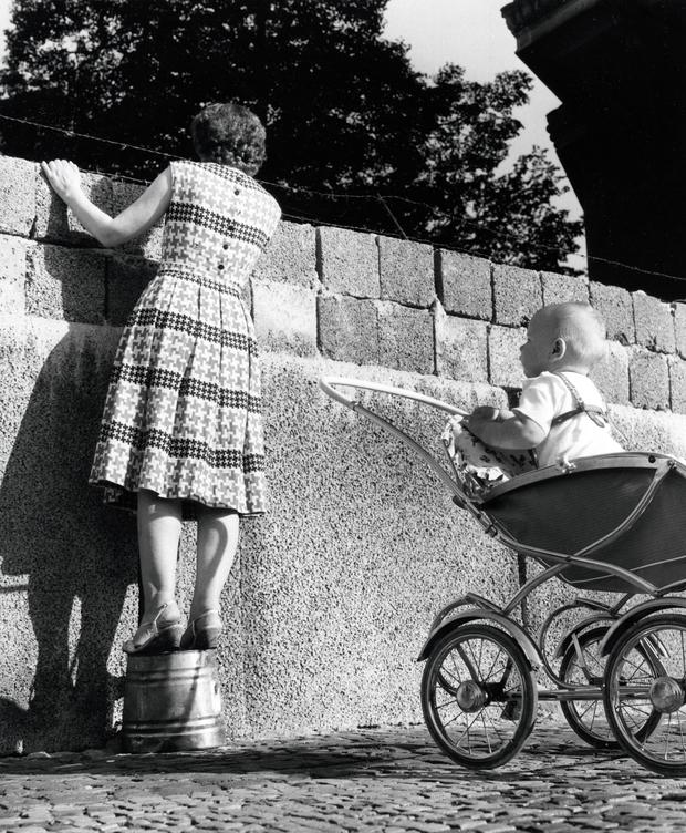 Blick nach „drüben“: Eine junge Mutter blickt über die Mauer in der Bernauer Straße in den Ostsektor.