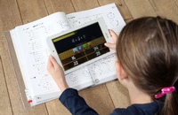 Mit Arbeitsbuch und Lernapp auf dem Tablet lernt eine Schülerin zu Hause. Foto: imago/epd/AnkexBingel