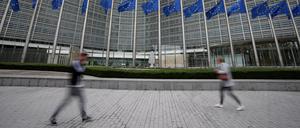 Die Flaggen der Europäischen Union wehen im Wind, während Fußgänger an der Zentrale der EU-Kommission vorbeigehen.