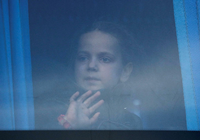 Ein Mädchen schaut durch das Busfenster, während Zivilisten, die aus dem Stahlwerk Azovstal in Mariupol evakuiert wurden, in einem provisorischen Unterkunftszentrum im Dorf Bezimenne ankommen. Foto: REUTERS/Alexander Ermochenko