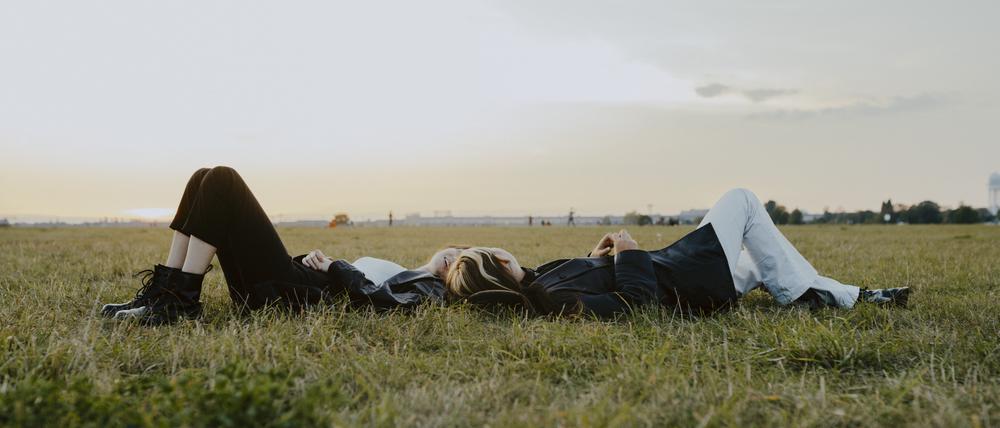 Female friends lying down on grass in park