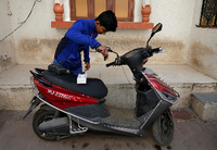 Ein junge im indischen Ahmedabad bereitet seinen E-Scooter zur Aufladung vor. Foto: REUTERS