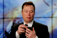 Elon Musk schaut bei einem Gespräch auf sein Smartphone. Foto: REUTERS/Joe Skipper/File Photo