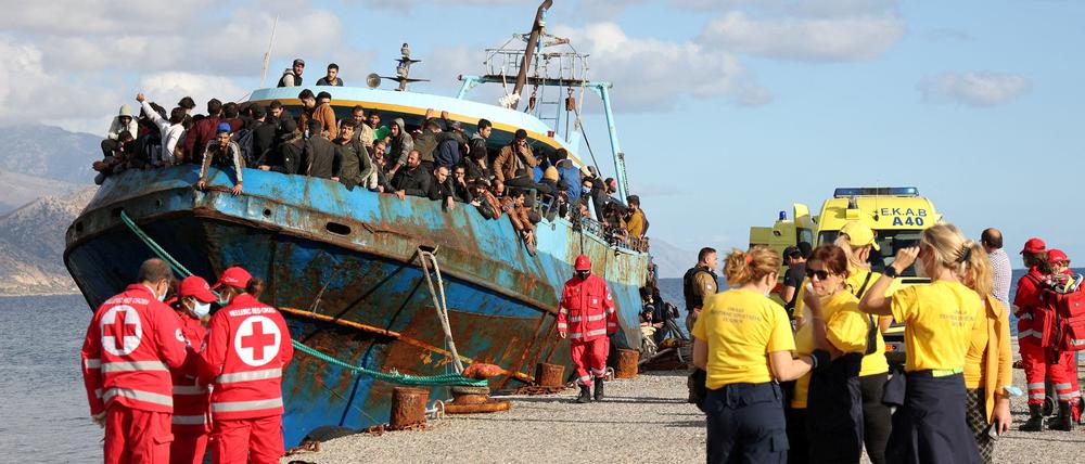 Mitarbeiter des Roten Kreuzes und Hilfsorganisationen neben einem Fischerboot mit Geflüchteten vor Kreta. 
