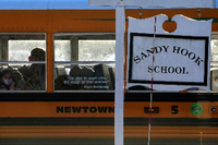 Ein Schulbus fährt an einem Schild mit der Aufschrift „Sandy Hook Schule“ vorbei. Foto: REUTERS/Carlo Allegri/File Photo