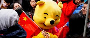 Ein Paradeteilnehmer in einem Winnie-Puuh-Kostüm schwenkt eine chinesische Flagge vor der Lunar New Year Parade im Stadtteil Chinatown in New York am 12. Februar 2023.