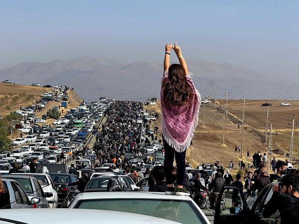 Eine unverschleierte Frau steht auf einem Fahrzeug, während sich Tausende auf den Weg zum Aichi-Friedhof in Saqez, der Heimatstadt von Mahsa Amini in der westiranischen Provinz Kurdistan, machen (Archivbild).