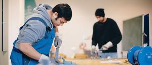 Der afghanische Flüchtling Sha Kah Ahmadi (l.) und der indischen Flüchtling Singh Satwinder feilen am 10.12.2015 in der Fortbildungsakademie der Wirtschaft (FAW) in Dresden (Saschen) an Metallwerkstücken.