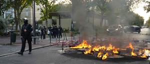Polizisten in Einsatzkleidung stehen neben einem Feuer, das nach einer Demonstration in Nanterre, westlich von Paris, am 27. Juni 2023 auf der Straße brennt.