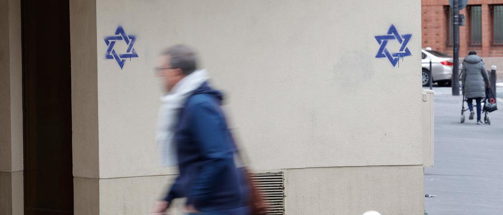 Ein Mann geht an einem Gebäude in Frankreich entlang, dessen Fassade nachts mit Davidsternen beschmiert wurde.
