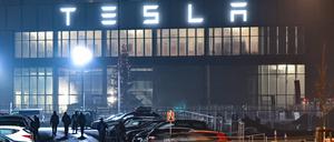 Brandenburg, Grünheide: Mitarbeiter gehen am frühen Morgen auf einem Parkplatz zum Werk des US-Elektroautobauers Tesla. 