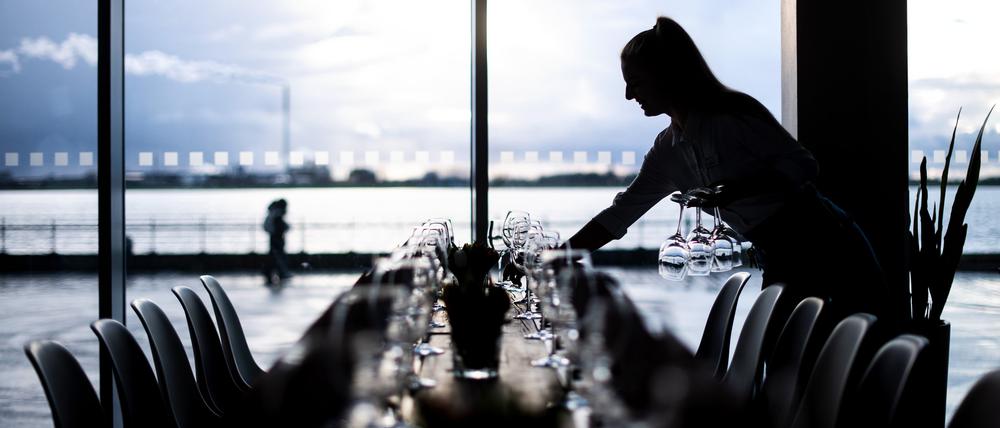 Eine Kellnerin deckt Tische im Restaurant Strom im Bremerhavener Atlantic Sail City Hotel. 