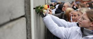 Schüler aus Deutschland, Frankreich und Norwegen steckten bei der zentralen Gedenkfeier zum 33. Jahrestag des Mauerfalls in der Gedenkstätte Berliner Mauer Rosen in die sogenannte Vorderlandmauer. 