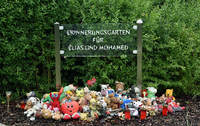 Eine Gedenktafel in der Kleingartenanlage in Luckenwalde erinnert an die ermordeten Kinder Elias und Mohamed. Foto: Ralf Hirschberger/dpa