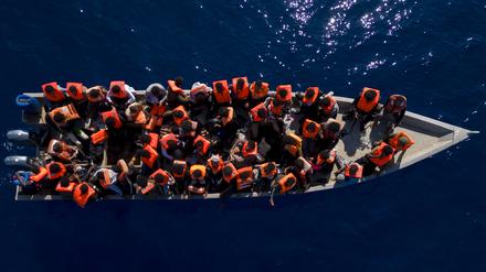 Migranten aus Eritrea, Libyen und dem Sudan sitzen in einem Holzboot.