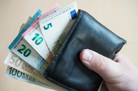 Geldscheine im Wert von fünf, zehn, zwanzig, fünfzig und hundert Euro stecken in einem Geldbeutel, der von einer Hand gehalten wird. Foto: picture alliance / Lino Mirgeler/dpa