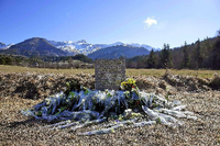 Inmitten von Blumen steht eine steinerne Gedenkstele mit der Aufschrift "In Erinnerung an die Opfer des Flugzeugunglücks vom 24. März 2015" in den vier Sprachen Englisch, Deutsch, Spanisch und Französisch in La Vernet, Frankreich, nahe der Unglücksstelle. Foto: dpa