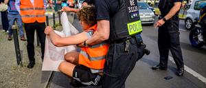 Ein Polizist schleift einen Aktivisten der „Letzten Generation“ von der Straße.
