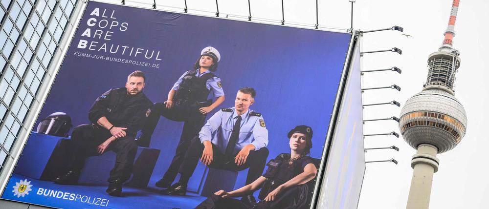 A billboard featuring a recruitment poster for Germany's federal police (Bundespolizei) is inscribed with the slogan "All Cops Are Beautiful", a play on the acronym ACAB (All Cops Are Bastards), in Berlin, on January 18, 2023, as the capital's landmark Television Tower (Fernsehturm) is seen in the background. (Photo by John MACDOUGALL / AFP)