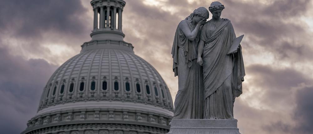 Blick auf das Friedensdenkmal und die Kuppel des US-Kapitols bei bewölktem Himmel. 