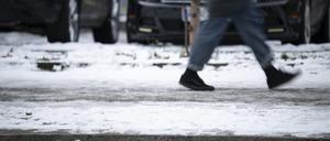 Ein Mensch läuft auf einem Gehweg. Die Folgen des Winterwetters in Berlin sind glatte Straßen und Gehwege.