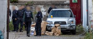 Polizisten stehen in einem Hinterhof in der Duisburger Innenstadt, auf dem Boden stehen Papiertüten mit Beweismitteln. 