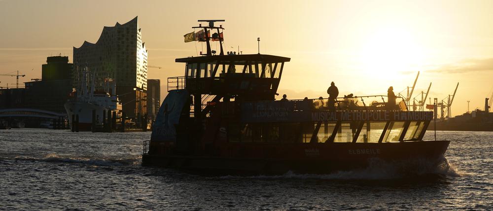 Eine Hafenfähre fährt im Sonnenaufgang auf der Elbe im Hamburger Hafen. 
