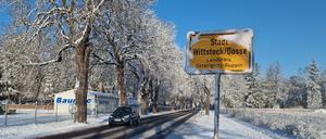 Das Ortseingangsschild von Wittstock/Dosse am verschneiten Straßenrand.  