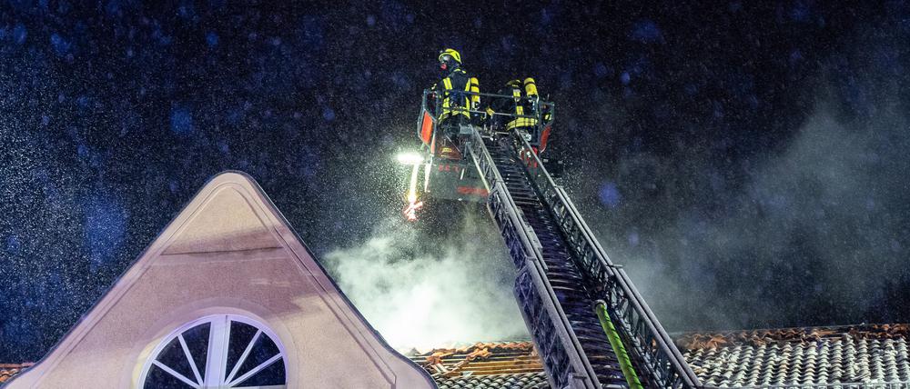 Die Feuerwehr löscht ein brennendes Dach.
