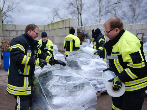 28.12.2023, Niedersachsen, Verden (Aller): Feuerwehrleute bereiten Sandsäcke vor.