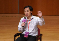 Bei einer Konferenz spricht He Jiankui in ein Mikrofon und gestikuliert. Foto: imago images/VCG