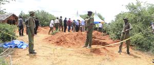 Polizeibeamte stehen neben Gräbern, aus denen die Polizei Opfer eines Sektenkults in Kenia exhumiert.