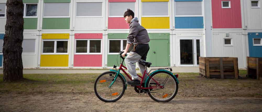 Ein Kind fährt vor einer Berliner Flüchtlingsunterkunft Fahrrad. (Archivbild)