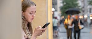 Eine junge Frau schaut am 30. Juli 2022 in München in ihr Smartphone.